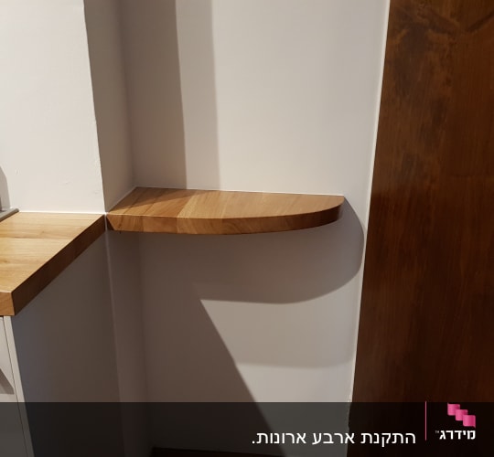 מדף עץ מעוגל מותקן על קיר לבן
